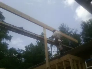 Carpenter setting a ridge beam over a new addition frame — Ice Dam Removal by Roofing Brothers in Colonia