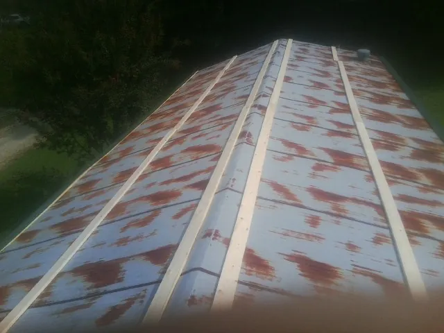 Rusted metal roof panels with new wood purlins before replacement — Storm Damage Roof Repair in Colonia by Roofing Brothers
