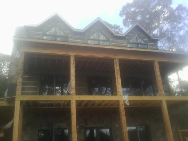 Dormers and porch framing on a large log home under construction — Roof Coating work by our crew in Colonia
